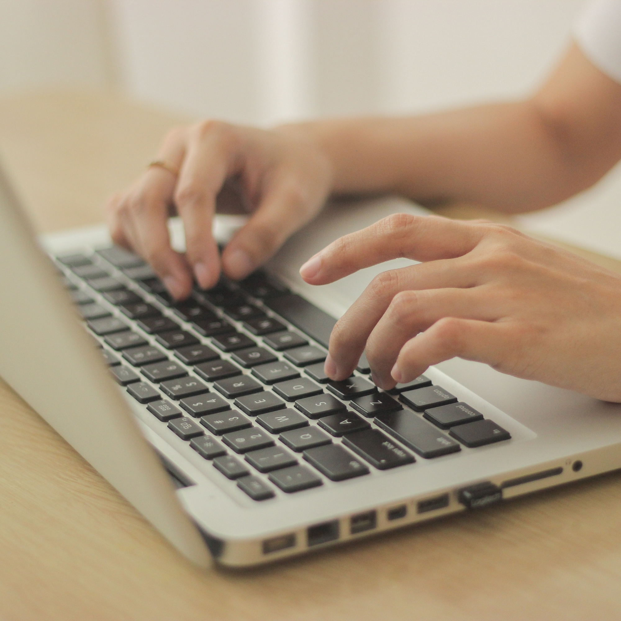 Person sitting in front of a desk and typing on the keyboard of the laptop otros servicios psicoterapia madrid
